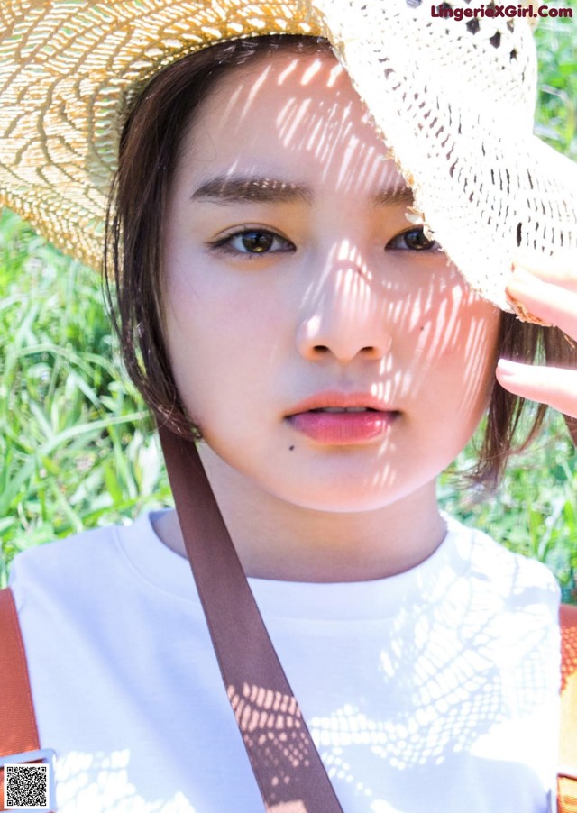 A woman wearing a straw hat and a white shirt.