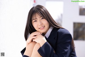 A young woman in a school uniform sitting on a bench.