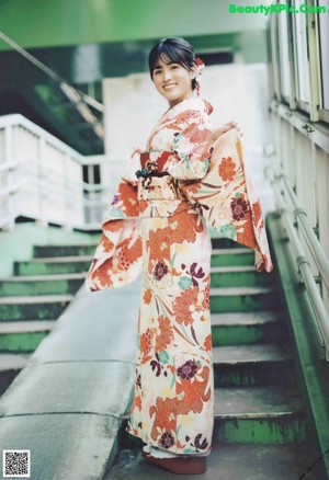 A woman in a kimono leaning against a wall.