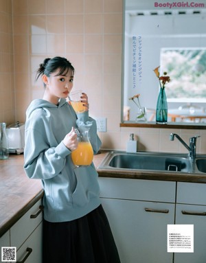 A woman standing in front of a bookshelf holding a bag.