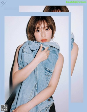 A woman in a denim vest is posing for a magazine.