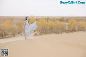 A woman in a blue dress standing in a field.
