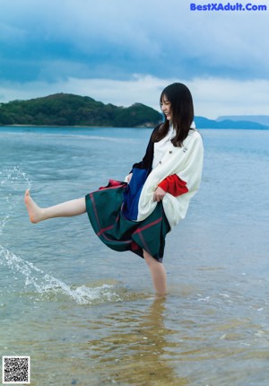 A woman sitting on a rock by the water.