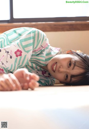 A woman laying on a bed holding a bottle of water.