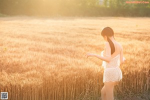 A woman in a white lingerie posing in a field.