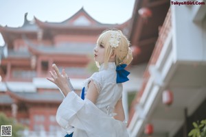 A woman in a white and blue dress standing on some steps.