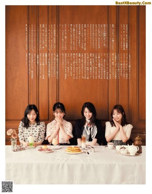 A group of young women sitting at a table with cups of coffee.