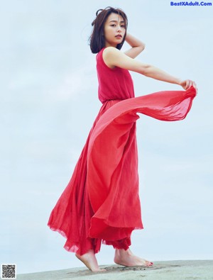 A woman in a blue dress sitting on the ground.