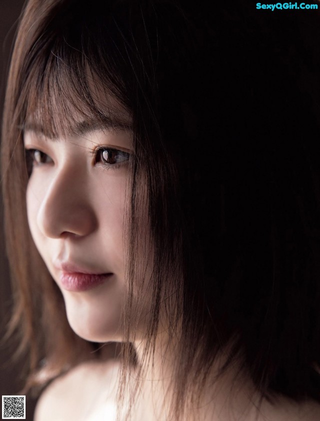 A woman with long brown hair is looking at the camera.