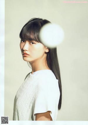 A woman in a white shirt is looking at the camera.
