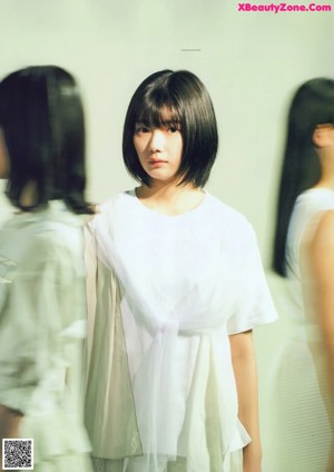 A woman with a black bob with bangs and a white shirt.