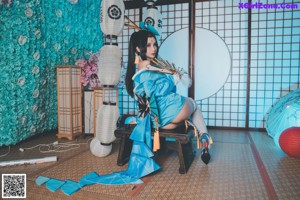 A woman in a blue and white outfit sitting on the floor.