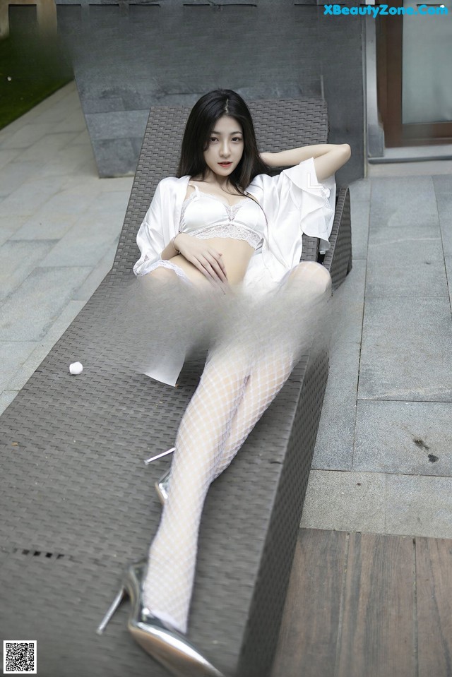 A woman in white lingerie sitting on a bench.