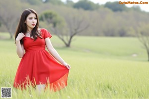 A woman in a red dress sitting on a bed.