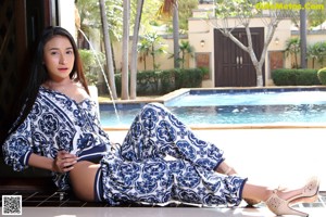 A woman sitting on the edge of a swimming pool.