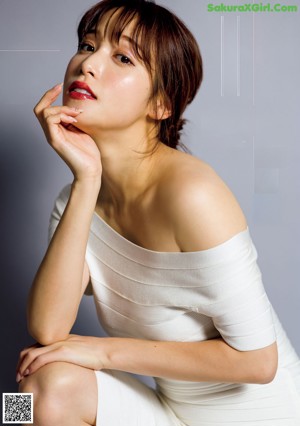 A woman in a white dress standing on a wooden floor.