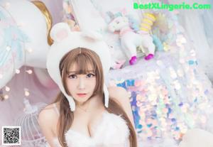 A woman in a white bunny costume pointing at herself in the mirror.