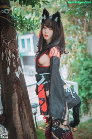 A woman in a black and red kimono sitting on the ground.