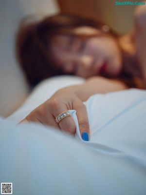 A woman laying on top of a bed next to a pillow.