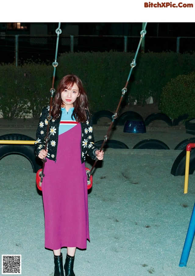 A woman standing on a swing in a park.