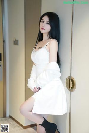 A woman in a black bra and white shirt posing for the camera.