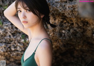 A woman in a green one piece swimsuit standing on a beach.