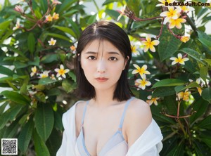 A woman in a white shirt and orange panties posing for a picture.