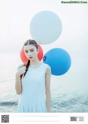 A woman in a white dress standing on the beach.