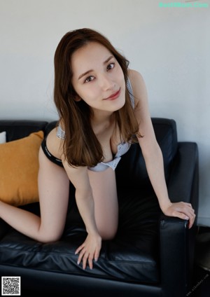A woman in a gray and white striped tank top and black panties.