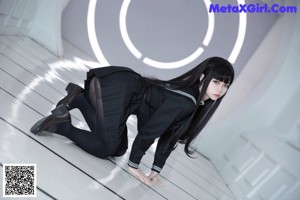 A woman in a black dress sitting on the floor.