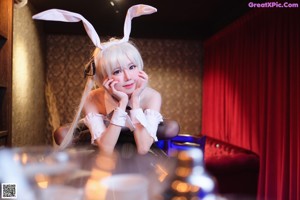 A woman in a bunny costume sitting on a bar.