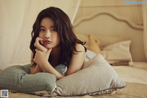 A woman sitting on top of a bed next to pillows.