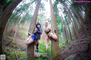 A couple of women sitting on top of a rock in the woods.