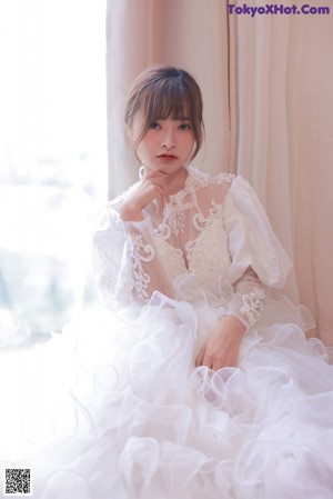 A woman in a wedding dress sitting on the floor.