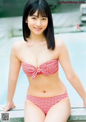 A woman in a white bikini leaning against a fence.