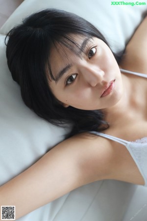 A woman laying on top of a bed with her arms behind her head.